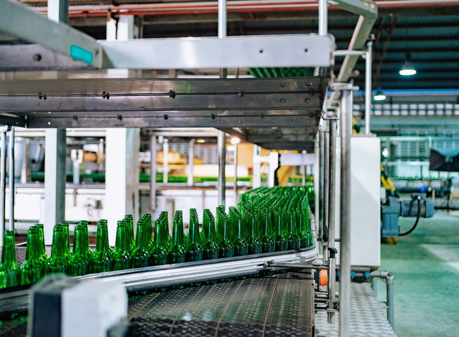Línea de producción con botellas de vidrio verde en una cinta transportadora, industria y packaging